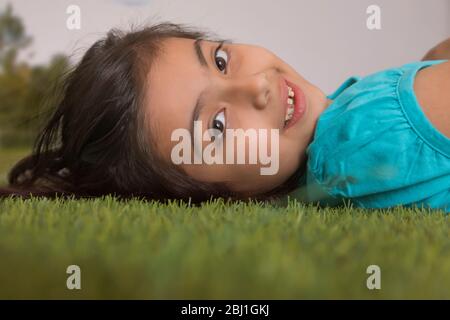 Junges Mädchen, das auf Gras liegt Stockfoto
