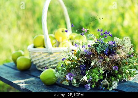 Grüne Äpfel mit Blumenstrauß auf Holztisch, Nahaufnahme Stockfoto