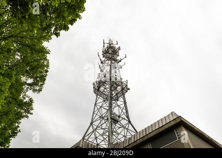 Mobilfunkturm. Antenne für Mobiltelefone und Bäume an einem bewölkten Tag. Stockfoto