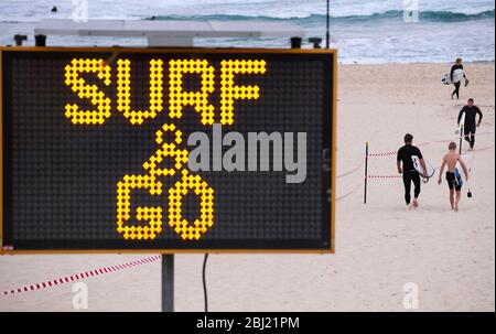 Sydney, Australien. April 2020. Surfer laufen am Bondi Beach in Sydney, Australien, am 28. April 2020. Hunderte von Aussies strömten am Dienstag zum Wasser, als der berühmte Bondi Beach nach der COVID-19 für Surfer und Schwimmer wieder geöffnet wurde. Kredit: Bai Xuefei/Xinhua/Alamy Live News Stockfoto