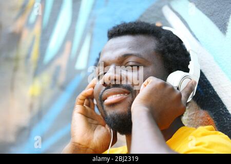 Afroamerikanischer Mann mit Kopfhörer auf Graffiti-Wand Hintergrund Stockfoto