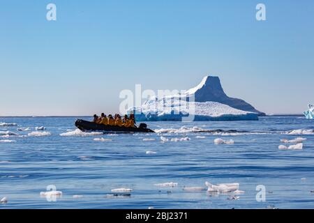 Eine Gruppe von Menschen, die in einem Zodiac Beiboot sitzen und durch Eisscholle auf der Antarktis segeln. Stockfoto