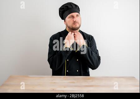 Junger männlicher Koch in schwarzer Uniform arrangiert seine Colla Stockfoto