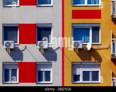 Klimaanlagenwand installierte Kondensatoreinheiten. Wohnfenster am Apartmentgebäude Außenwand- oder Fassadendetails. Bunte Stuck-Isolierung Stockfoto