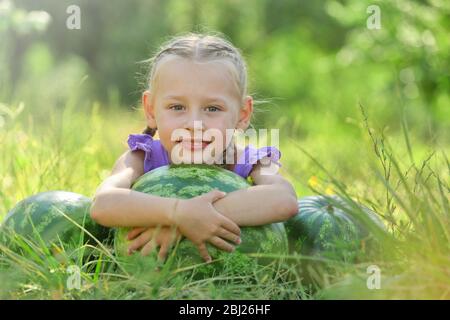 Kleines Mädchen mit Wassermelonen auf dem Rasen Stockfoto