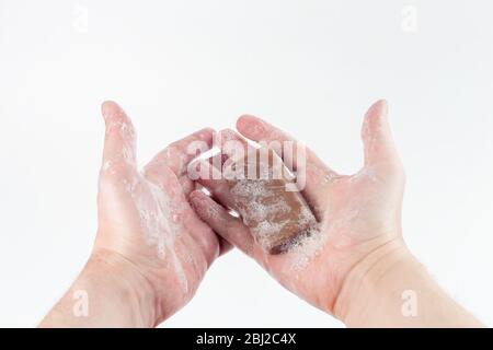 Ein nasses Stück brauner Teerseife in menschlichen Händen Auf weißem Hintergrund Stockfoto