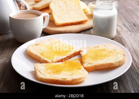 Brot mit Butter und hausgemachte Marmelade in weißem Teller auf Holztisch, Nahaufnahme Stockfoto