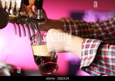 Der Barkeeper gießt Bier ins Glas Stockfoto