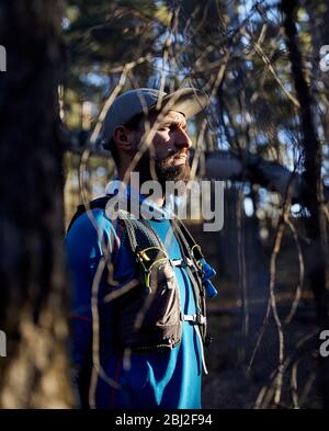Portrait von Runner Athlet mit Bart im blauen Hemd im Wald Stockfoto