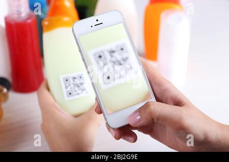 Frau scannt Gutschein-Code mit Handy aus nächster Nähe Stockfoto