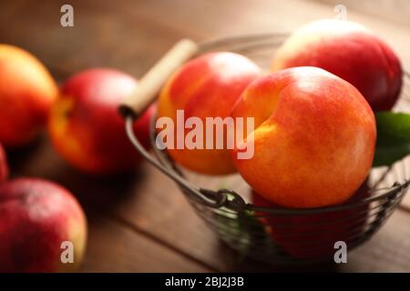Frische Pfirsiche in Weidenkorb auf hölzernen Hintergrund Stockfoto