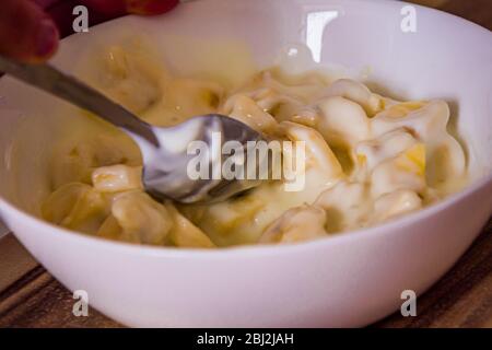 Mischen Bananenstücke mit Naturjoghurt in einer weißen Schüssel Stockfoto