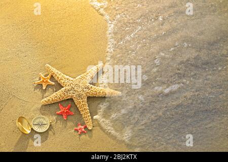 Kompass mit Seesternen auf Sand Strand Hintergrund Stockfoto
