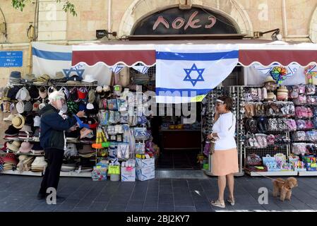 Jerusalem, Israel. April 2020. Israelis tragen wegen der COVID-19-Pandemie Gesichtsschutzschilde vor einem Geschäft, in dem die Nationalflagge gezeigt wird, zum Gedenktag und zum Unabhängigkeitstag am Dienstag, den 28. April 2020 in Jerusalem. Foto von Debbie Hill/UPI Quelle: UPI/Alamy Live News Stockfoto