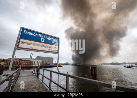 Bremen, Deutschland. April 2020. Rauch zieht über den Industriehafen. Im Gröpelinger Bezirk brennen mehrere benachbarte Lagerhäuser. Quelle: Sina Schuldt/dpa/Alamy Live News Stockfoto