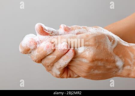 Nahaufnahme der Frau, die Hände mit Seife auf grauem Hintergrund wäscht. Hygienische Prävention der Desinfektion des Coronavirus-Virus. Stockfoto