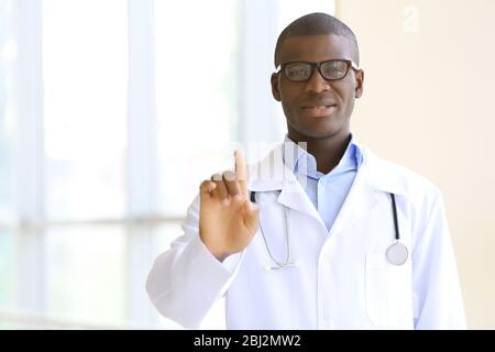 Schöner afroamerikanischer Arzt mit Stethoskop im Krankenhaus Stockfoto