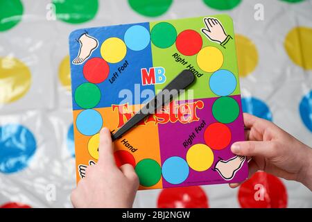 Ein Junge dreht die Twister Spiel Spinner vor seinem auf der Matte gehen. Stockfoto