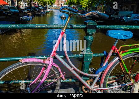 Altes mehrfarbiges Vintage-Fahrrad auf einer Brücke auf einem Kanal in Amsterdam, Niederlande Stockfoto