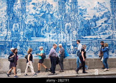 Menschen passieren Azulejos Portugiesische blaue und weiße Wandfliesen von Capela das Almas de Santa Catarina - St. Katharinenkapelle in Porto, Portugal Stockfoto