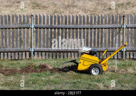 Bagger graben Boden, um Bewässerungssystem für Pflanzen im Garten zu machen. Landwirtschaftliche Maschine Bagger Schmutz zu installieren Tropfbewässerung System Stockfoto