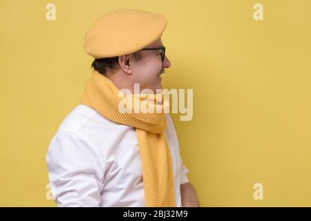kaukasischer Mann in gelbem Schal und Hut, der zur Seite schaut. Stockfoto