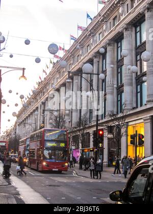 Rote Doppeldeckerbusse vor dem Kaufhaus Selfridge in der Oxford Street, London, mit weihnachtlichen Dekorationen, die über die Straße gezogen sind Stockfoto