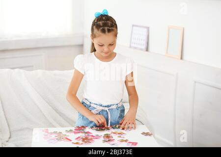 Nettes kleines Mädchen, das mit Puzzles auf Home Interior Hintergrund spielt Stockfoto