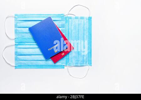 Zwei ausländische Pässe in blauen und roten Farben sind auf medizinischen Masken auf einem hellen Hintergrund. Welt Quarantäne Konzept. Flaches Lay. Kopierbereich Stockfoto