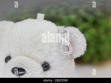 Schöne Infinity-Form silbernen Ring mit Diamanten Display auf Spielzeug Bär verziert Stockfoto