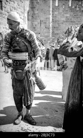 In den frühen 1940er Jahren verkauft ein Limonadenverkäufer an einen jungen Jungen auf den Straßen Jerusalems Stockfoto