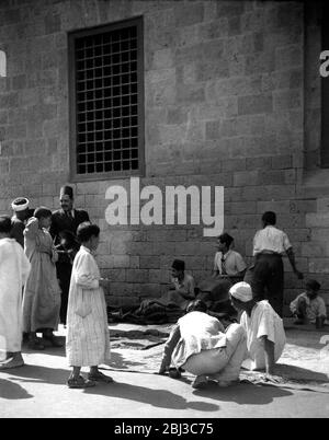 Eine Gruppe von Teppichmandelern hat ihren Handel in den 1940er Jahren auf den Straßen von Kairo, Ägypten, an der Zitadellenmauer, geführt. Stockfoto