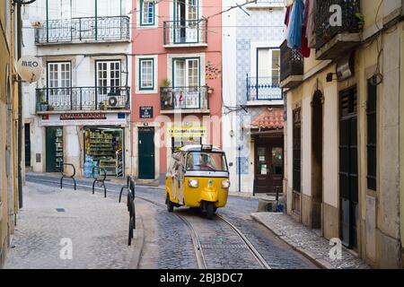 Piaggio Ape Tuk Tuk Typ Dreirad-Personenwagen und Straßenbahnschienen, schmale steile Einkaufsstraße in Alfama District, Lissabon, Portugal Stockfoto