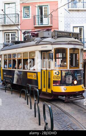 Historische berühmte Straßenbahn Nummer 28, die Einheimische und Touristen auf Tramgleisen entlang der engen Straße im Stadtteil Alfama, Lissabon, Portugal, transportiert Stockfoto