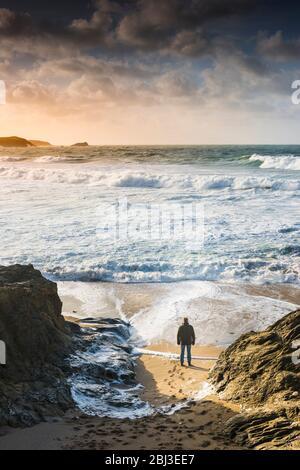 Ein Mann allein am Strand und beobachten die ankommenden Wellen in eine stürmische See an wenig Fistral in Newquay in Cornwall. Stockfoto