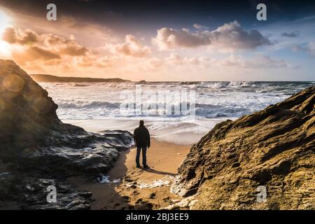 Ein Mann allein am Strand und beobachten die ankommenden Wellen in eine stürmische See an wenig Fistral in Newquay in Cornwall. Stockfoto