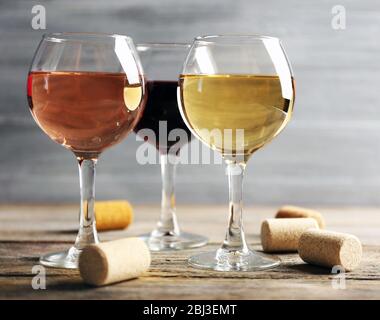 Zusammensetzung von Weingläsern und Korken auf Holztisch vor grauem Hintergrund Stockfoto