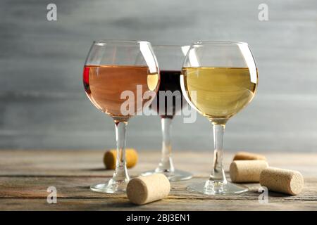 Zusammensetzung von Weingläsern und Korken auf Holztisch vor grauem Hintergrund Stockfoto