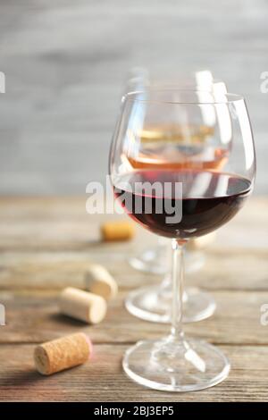 Weingläser in Reihe und Korken auf Holztisch vor grauem Hintergrund Stockfoto