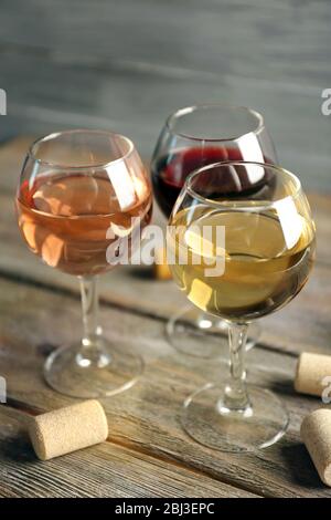 Zusammensetzung von Weingläsern und Korken auf Holztisch vor grauem Hintergrund Stockfoto