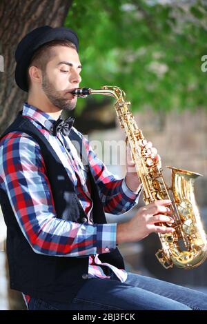 Schöner junger Mann spielt Saxophon im Freien Stockfoto