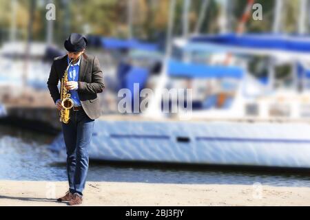 Schöner Mann spielt Saxophon vor der Yacht Stockfoto