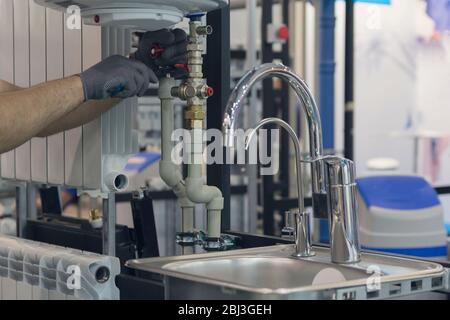 Hände von professionellen Klempner mit einem Wasserhahn und Schraubenschlüssel. Sanitäre Arbeiten Stockfoto