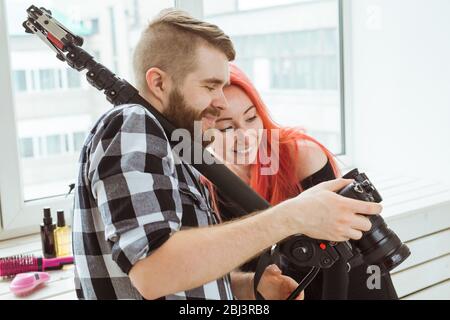 Videoproduktion, Werbeaufnahmen und Inhalte für soziale Netzwerke - Betreiber arbeitet mit einer Kamera auf der Schulter und zeigt die Mädchen Filmmaterial. Stockfoto