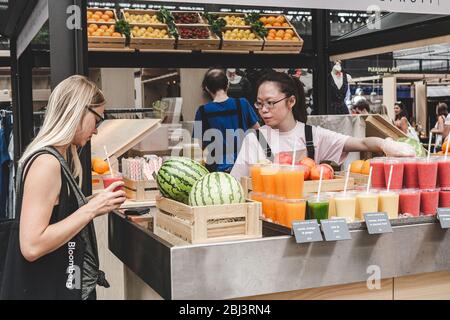 London/UK - 22/07/18: Frau kauft frisch zubereiteten Obst Smoothie in einem Stand in der Spitalfields Market, Händler-Markt sowie ein Lebensmittel-und Kunst ma Stockfoto