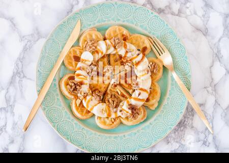 Belgien herzförmige Waffeln mit Bananen, Ahornsirup, gesalzenem Karamell und Nüssen. Draufsicht. Stockfoto