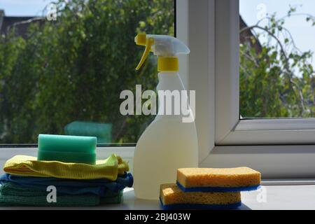 Sprühflasche, Schwämme und Reinigungstücher auf Fensterbank Stockfoto