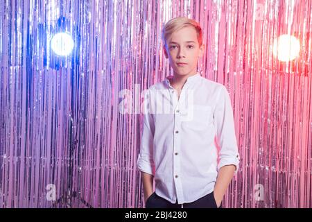 Peinlich Alter und Teenager-Konzept - Porträt von Teenager-Jungen auf einer Party. Glänzender Hintergrund. Stockfoto