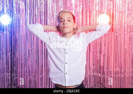 Peinlich Alter und Teenager-Konzept - Porträt von Teenager-Jungen auf einer Party. Glänzender Hintergrund. Stockfoto