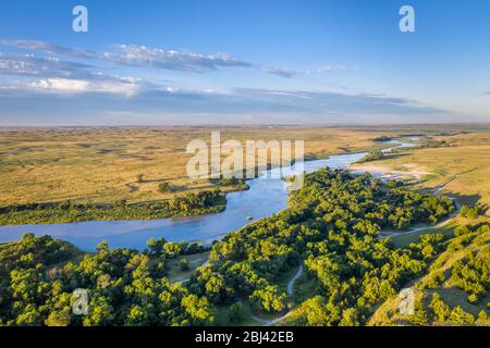 Seichter und breiter düsterer Fluss, der durch Nebraska Sandhills im Nebraska National Forest fließt, Luftaufnahme der morgendlichen Sommerlandschaft Stockfoto